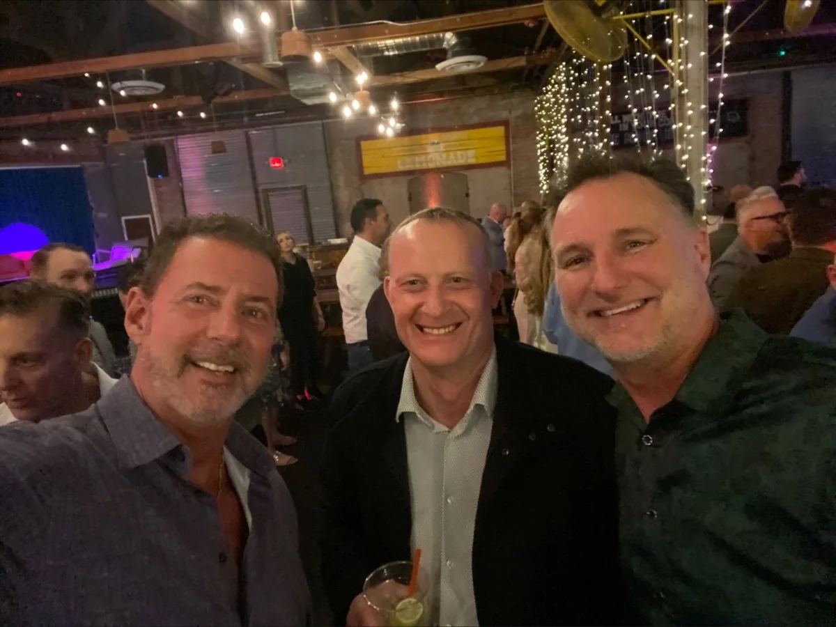 Rob Lancit, Stewart and Mike Millett smiling together at an evening event